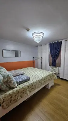 a bedroom with a bed and a chandelier at Bright & Airy Loft Cambridge Village Charm in Cainta
