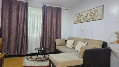 a living room with a couch and a window at Bright & Airy Loft Cambridge Village Charm in Cainta