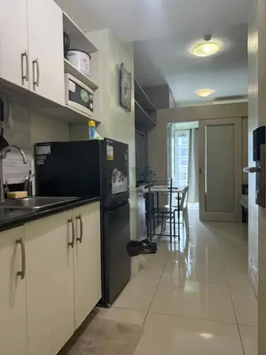 a kitchen with white cabinets and a black refrigerator at 1BR Staycation at JAZZ Makati 29F 65 Smart TV in Manila