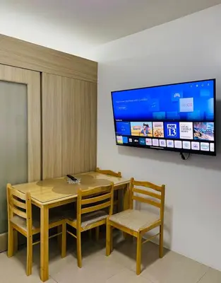 a dining room with a table and chairs and a tv at Shore 1 Residences in Manila