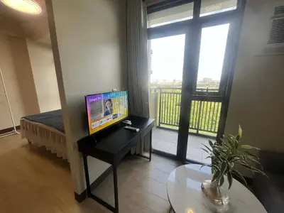 a room with a desk with a television and a balcony at Gentry Manor WiFi Netflix&Balcony Near Okada NAIA in Manila
