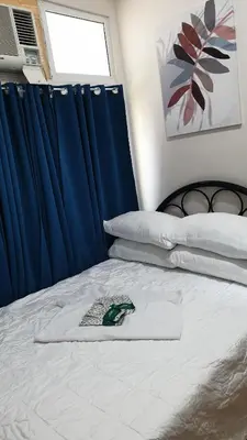 a bedroom with a bed with a blue curtain at AC's Suite in Manila