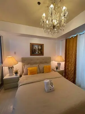 a large bedroom with a large bed with a chandelier at Azure Resort Condo with Man-Made Beach Pool in Manila
