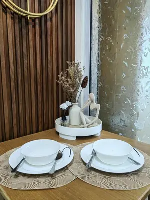a table with two white plates and a vase at Panatag Staycation by Yani at Azure Urban Residences, Parañaque in Manila