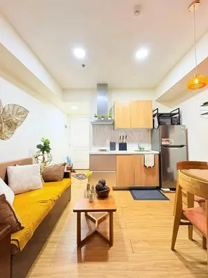 a living room with a yellow couch and a kitchen at Panatag Staycation by Yani at Azure Urban Residences, Parañaque in Manila