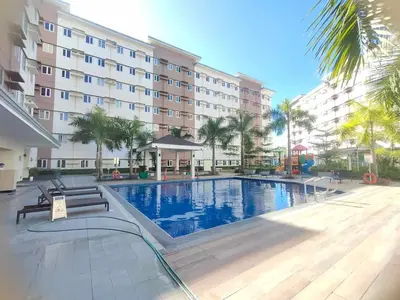 a hotel with a swimming pool in front of a building at Beirut Bliss Suite at Hope Residences Trece Martires in Trece Martires