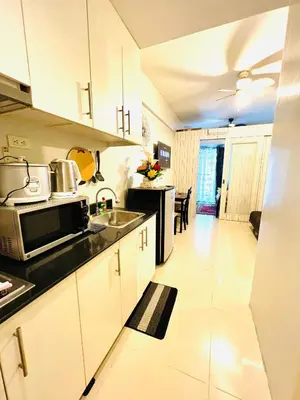 a kitchen with white cabinets and a black appliances at Sea Residences Elegant Place by Paul in Manila