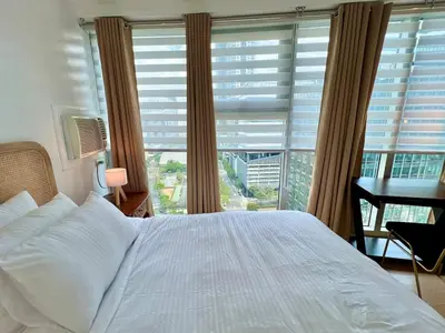 a bedroom with a bed and a desk and a window at Charming 2-BR Condo in BGC in Manila