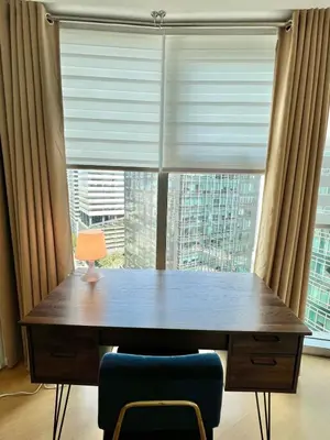 a wooden table with a lamp in front of a window at Charming 2-BR Condo in BGC in Manila