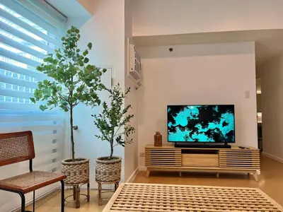 a living room with two trees and a television at Charming 2-BR Condo in BGC in Manila
