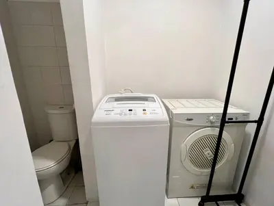 a small bathroom with a washing machine and a toilet at Charming 2-BR Condo in BGC in Manila
