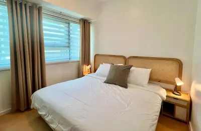 a bedroom with a white bed with a window at Charming 1-BR in BGC in Manila