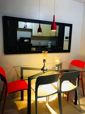 a dining room with a glass table and red chairs at Apartment near Airport at One Palm Tree Villas in Manila