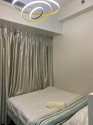 a bedroom with a bed with a chandelier above it at AIR RESIDENCES MAKATI Staycation in Manila