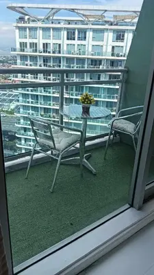 a table and chairs on a balcony with a view of a building at AZURE RESIDENCES near International AIRPORT MANILA in Manila