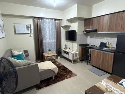 a living room with a couch and a kitchen at 1BR Staycation at Avida Towers SM Sucat in Manila