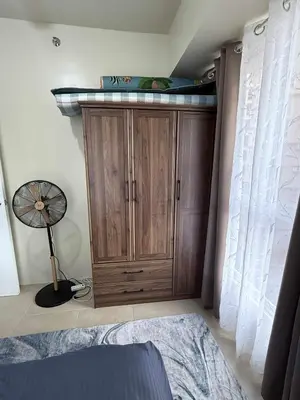 a bedroom with a wooden cabinet and a fan at 1BR Staycation at Avida Towers SM Sucat in Manila