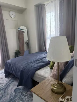 a bedroom with a bed and a table with a lamp at 1BR Staycation at Avida Towers SM Sucat in Manila