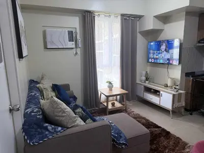 a living room with a couch and a flat screen tv at 1BR Staycation at Avida Towers SM Sucat in Manila