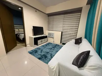 a living room with a white couch and a television at 1 Bedroom Apartment Across NAIA T3 in Manila