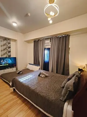 a bedroom with a large bed and a television at Holland Park staycation in Jalang