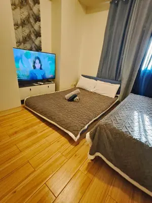 a bedroom with two beds and a flat screen tv at Holland Park staycation in Jalang