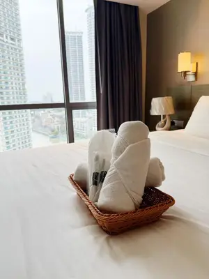 a basket of towels on a bed in a hotel room at Metro Suites at Novotel Suites Acqua in Manila