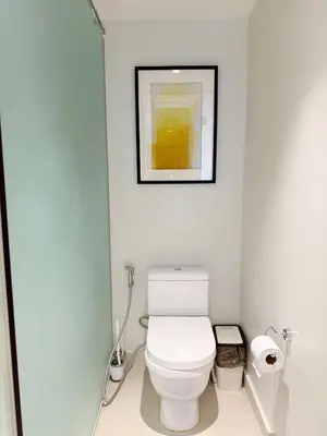 a bathroom with a white toilet with a picture on the wall at Metro Suites at Novotel Suites Acqua in Manila