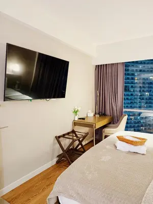 a bedroom with a bed and a desk and a window at Metro Suites at Novotel Suites Acqua in Manila