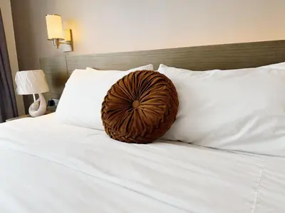 a wooden ball on a bed with white pillows at Metro Suites at Novotel Suites Acqua in Manila