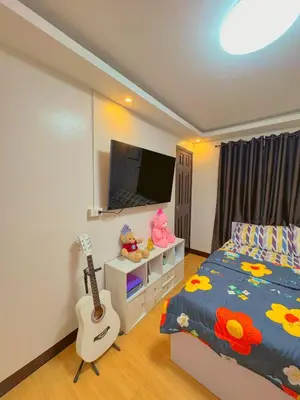a bedroom with a bed with a guitar and a tv at Gabrielle Staycation in Imus