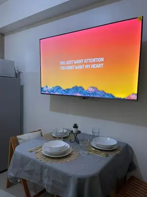 a table with two plates and a projection screen on a wall at Casa California by AC Haven in Shore Residences near MOA Pasay City in Manila