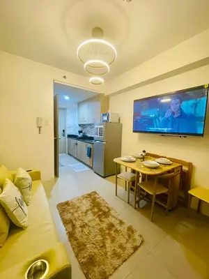 a living room with a table and a tv on the wall at Casa California by AC Haven in Shore Residences near MOA Pasay City in Manila