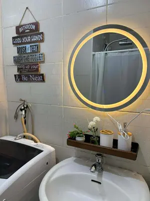 a bathroom with a sink and a round mirror at Cozy City Escape - Jazz Residences in Manila