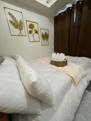 a white bed with a basket on top of it at Cozy City Escape - Jazz Residences in Manila
