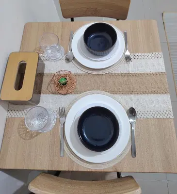 a wooden table with two plates and silverware on it at Cozy City Escape - Jazz Residences in Manila