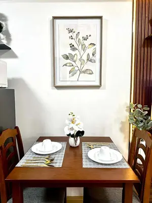 a wooden table with two plates and a picture on the wall at Candice Empire Garden in Manila