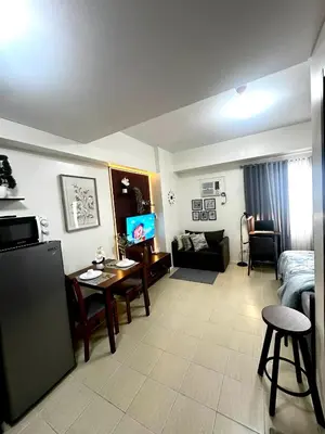 a living room with a room with a bed and a television at Candice Empire Garden in Manila