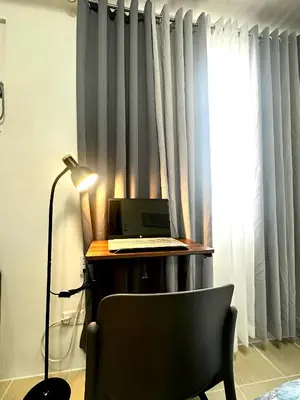 a desk with a laptop and a chair next to a window at Candice Empire Garden in Manila