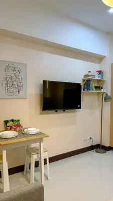 a dining room with a table and a tv on the wall at A Studio Unit in McKinley Near Venice Grand Canal Mall in Manila
