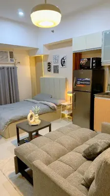a living room with a couch and a kitchen at A Studio Unit in McKinley Near Venice Grand Canal Mall in Manila