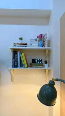 a lamp sitting next to a shelf with books at A Studio Unit in McKinley Near Venice Grand Canal Mall in Manila