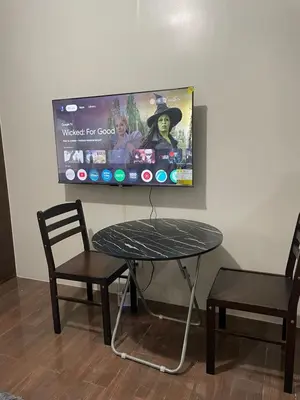 a table and two chairs and a tv on a wall at Hailar Property Management in Manila