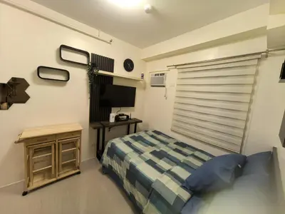 a bedroom with a bed and a flat screen tv at FSZAirbnb in Manila