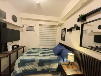 a small bedroom with a bed and a television at FSZAirbnb in Manila