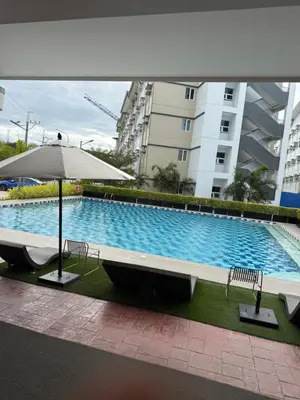 a swimming pool with two chairs and an umbrella at Park Residences 201 - Sta Rosa Laguna