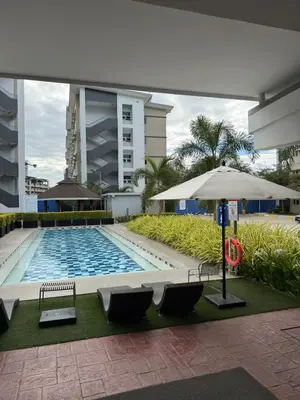 a swimming pool with benches and an umbrella at Park Residences 201 - Sta Rosa Laguna