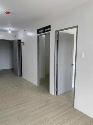 an empty hallway with three open doors in a building at Cozy oozy apartment in Manila