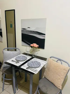 a dining table with two chairs and a table with glasses at The Cozy Nook in Manila
