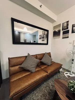a brown leather couch in a living room with a mirror at The Baylight Escape at Shore 2 in Manila